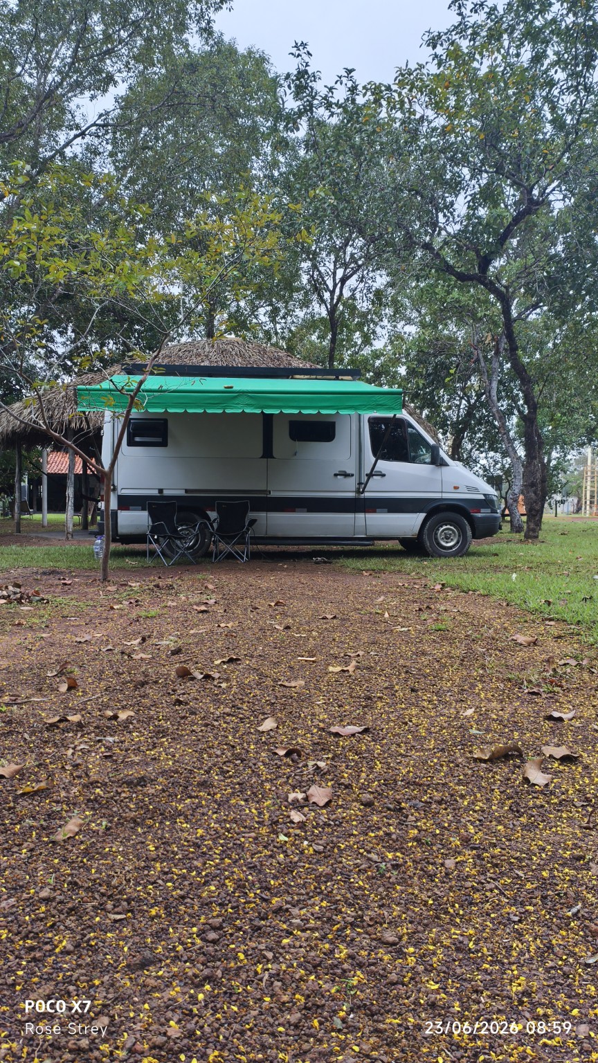 Motorhome estacionado na área de camping sombreada do Refúgio